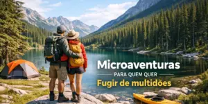 Casal em trilha à beira de lago cercado por montanhas e floresta, com barraca e caiaque.